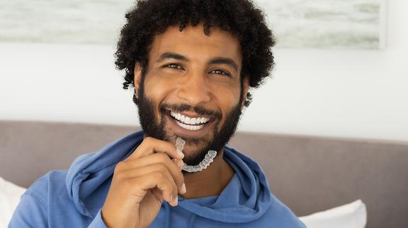 man-in-bedroom-holding-clear-aligners